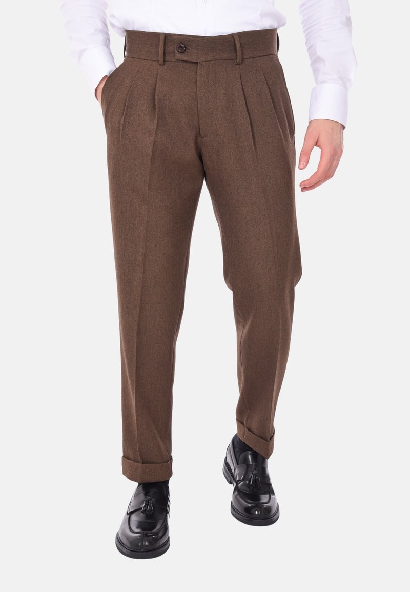 Pantaloni marroni plissettati realizzati in tessuto texturizzato, con una vita dotata di un bottone singolo e orli arrotolati. Abbinati a scarpe eleganti nere.