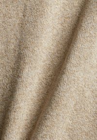 Tissu tricoté beige avec une texture fine, présentant un motif subtil de fibres entrelacées. Doux et dégageant des nuances légèrement variées de brun clair.