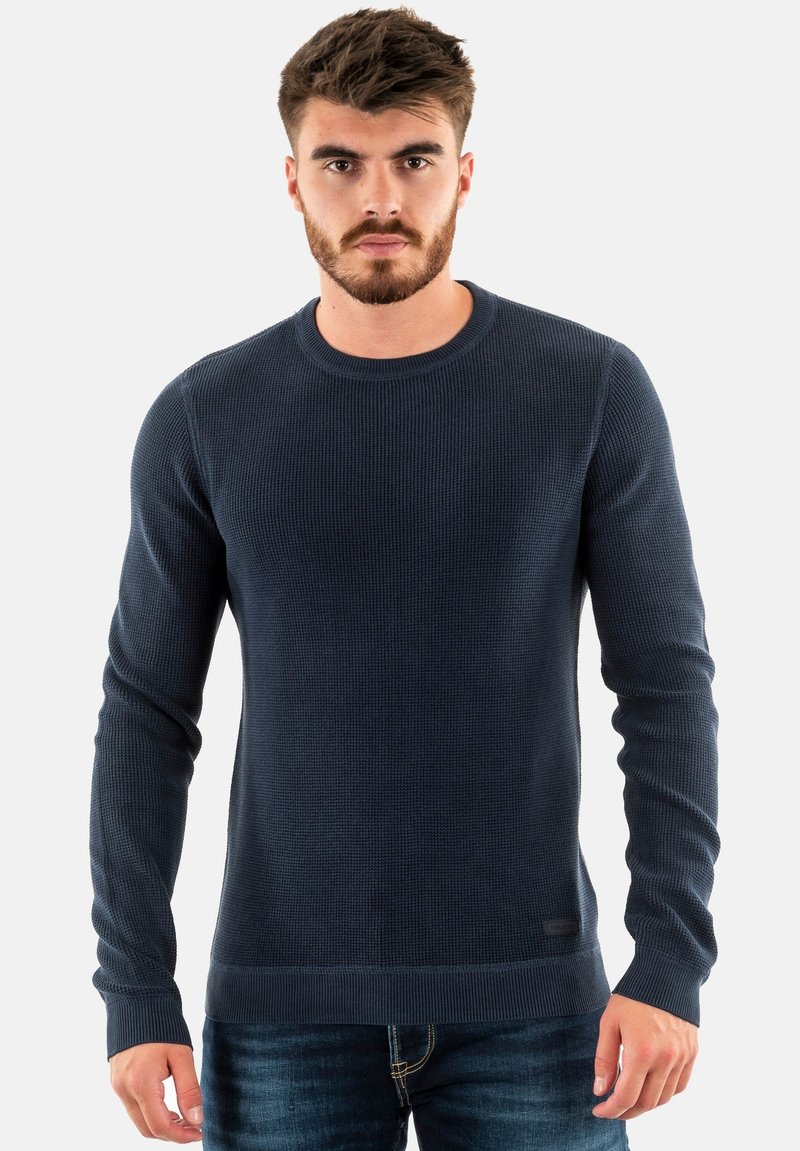 Maglione in maglia a costine blu navy con scollatura rotonda, maniche lunghe e tessuto testurizzato, caratterizzato da un'etichetta discreta sull'orlo e un design aderente.