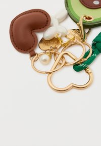 Avainpidike, jossa on ruskea nahkasydän, kultaiset metalliosat, vihreät ja vaaleanpunaiset koristeet, helmityypit ja punottu vihreä nahkahihna. Eri muotoisia avainrenkaita.