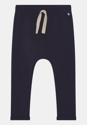 Pantalones jogger azul marino hechos de tela suave, con cintura elástica, cordón beig y puños en los tobillos.