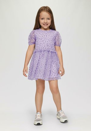 Lila Kleid mit Puffärmeln, strukturiertem Punktmuster und Schichtenrock. Kombiniert mit weißen und grauen Sportschuhen. Glattes Material.
