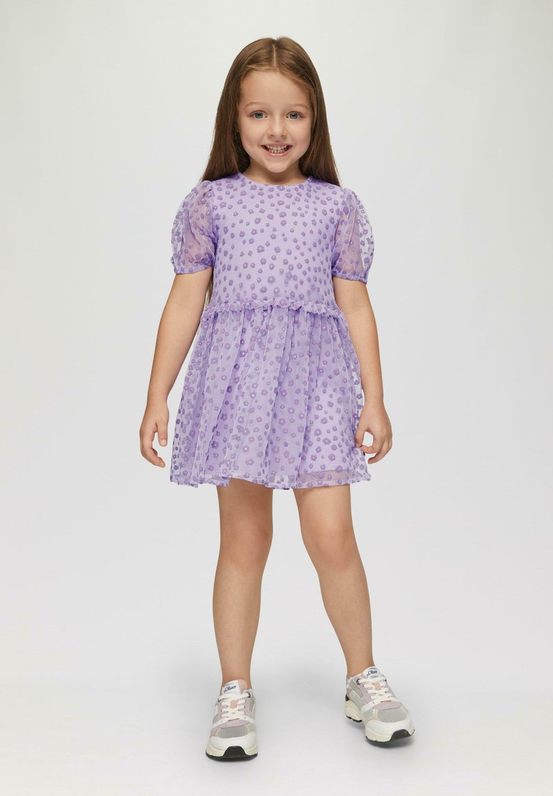 Lila Kleid mit Puffärmeln, strukturiertem Punktmuster und Schichtenrock. Kombiniert mit weißen und grauen Sportschuhen. Glattes Material.