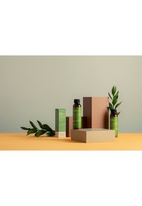 Grön lotionflaska och låda på orange yta, med bruna geometriska block och gröna blad. Minimalistisk design, släta texturer och jordnära färger.