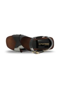 Sandal in pelle verniciata nera con suola in legno, caratterizzata da cinturini incrociati, una fibbia dorata e piccole borchie decorative.