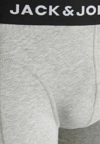 Graue Baumwoll-Boxershorts mit einem schwarzen elastischen Bund, der mit weißem "JACK & JONES"-Text versehen ist. Sichtbare Nähte entlang der Säume.