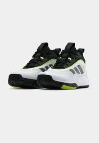 Λευκά και μαύρα αθλητικά παπούτσια με φωσφοριζέ πράσινες λεπτομέρειες. Πάνω μέρος από διχτυωτό υλικό, ελαστική σόλα, χαρακτηριστική υφή στο πέλμα και δετό σχέδιο με κορδόνια.