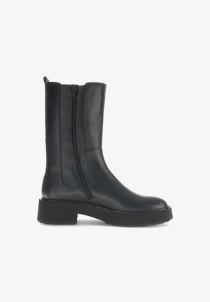 Bota de tornozelo em couro preto com fecho lateral, bico arredondado e sola de borracha grossa. Apresenta detalhes de costura ao longo das bordas.