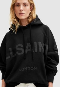 Felpa nera con cappuccio dal taglio rilassato, caratterizzata da testo in rilievo "ALLSAINTS" e "LONDON" con una finitura opaca contrastante. Tessuto morbido.