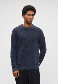 Camisola de malha canelada azul-marinho com decote redondo, mangas compridas e detalhes texturizados contrastantes nos punhos e na barra.