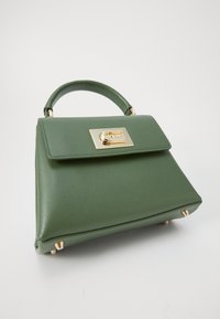 Sac à main en cuir vert au design structuré, avec un détail de fermoir en or et une petite poignée. Présente une surface texturée et quatre pieds métalliques.