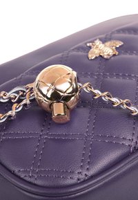 Borsa a mano in ecopelle trapuntata viola con chiusura a sfera in tonalità oro e tracolla in argento, decorata con un piccolo dettaglio a forma di ape.