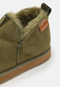 Zielone zamszowe botki za kostkę z miękką, puszystą podszewką i trwałą gumową podeszwą. Posiada przeszywane akcenty oraz panel marki oznaczony napisem "SHEPHERD."