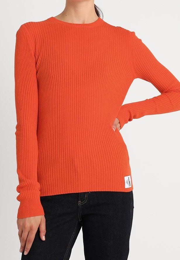 Ribbad orange långärmad tröja med rund halsringning. Har en märkesetikett på nederkanten och åtsittande ärmar.