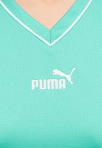 Τζελ αθλητική μπλούζα με λευκό λογότυπο Puma στο κέντρο,  ακριβώς κάτω από ένα λαιμόκοψη σχήματος V με λευκή επένδυση.