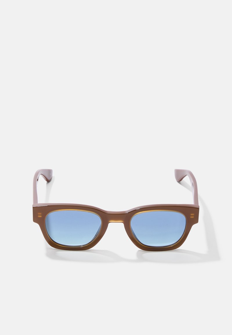 Lunettes de soleil en plastique marron avec des verres dégradés bleus, de forme rectangulaire et branches légèrement courbées. Détail remarquable : accents marron clair sur la monture.