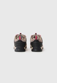 Un paio di sneaker nere, beige e rosse viste da dietro su uno sfondo bianco semplice, dotate di linguette di trazione e colli imbottiti.