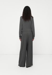 Grijze trui met lange mouwen, gecombineerd met brede, geruite broek in grijstinten. Zachte stof met een elastische tailleband.