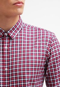 Rood en marineblauw geblokt overhemd met knopen en een klassieke kraag, gemaakt van geweven stof met een zachte textuur en witte accenten in het patroon.