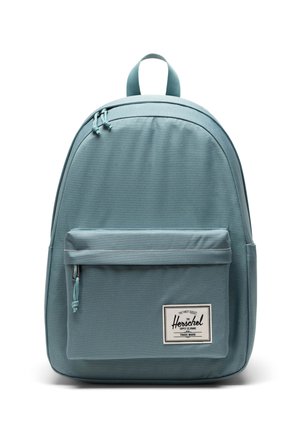 Lyseblå rygsæk lavet af holdbart stof, med en forreste lynlåslomme, justerbare stropper og et topgreb for nem bæring.