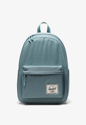 Jasnoniebieski plecak wykonany z trwałej tkaniny, wyposażony w przednią kieszeń na zamek, regulowane paski oraz górny uchwyt ułatwiający przenoszenie.