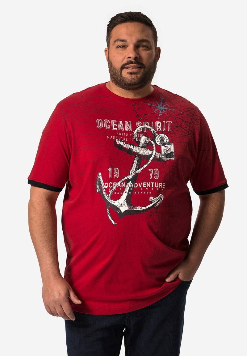 Camiseta roja de manga corta con un gran gráfico de ancla blanca, detalles en negro en las mangas y texto impreso. Fabricada en algodón, de corte casual.