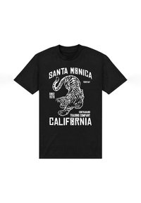 Camiseta negra con un gráfico blanco de un tigre, texto "Santa Mónica", "Trading Company" y "California", con elementos de estilo vintage.