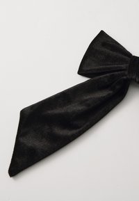 Black velvet bow tie with a textured surface, featuring a wide knot and two elongated, tapered ends. The fabric has a soft sheen.