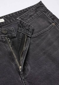 Jeans in denim nero con zip, chiusura a bottone e tasche. Tessuto testurizzato con sottili righe orizzontali.