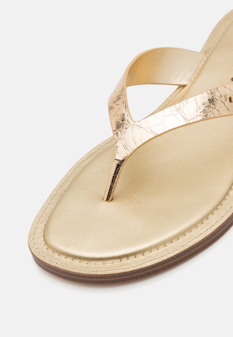 Złote sandały na cienkim pasku z metalicznym, teksturowanym paskiem i gładką, błyszczącą wkładką. Posiada brązowe, przeszyte kontury i zwężający się pasek między palcami.