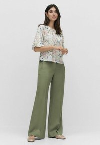 Blomstret bluse med puffede ærmer, kombineret med høj talje, brede olivengrønne bukser. Blødt stof, lyse farver og afslappet pasform.