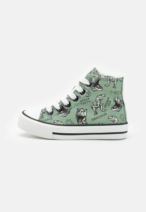Baskets montantes vertes avec semelle et lacets blancs, décorées d'illustrations noires de dinosaures et de textes tels que "T-Rex" et "Sharp Teeth."