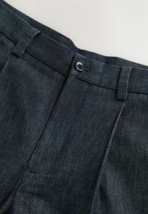 Dunkelblaue Jeans mit glatter Textur, ausgestattet mit einem Reißverschluss und Knopfverschluss, taillierter Schnitt und dezenten Nähten.