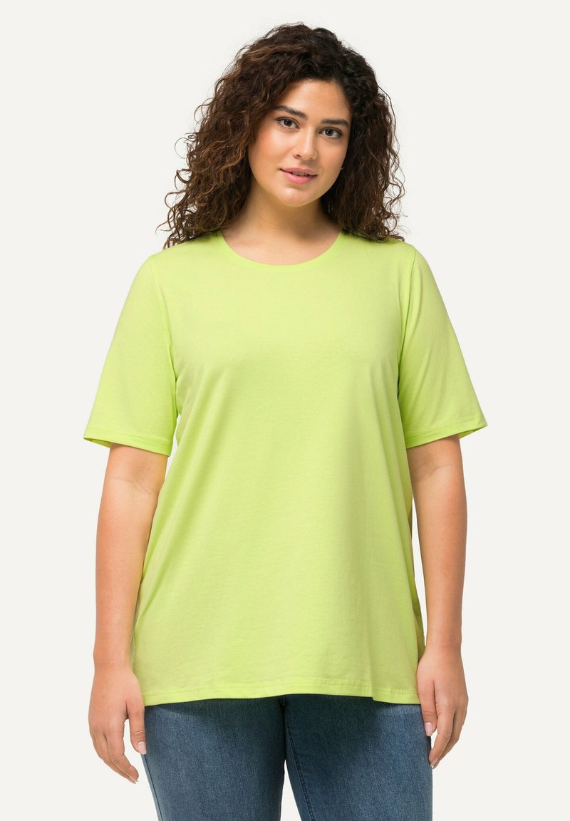T-shirt verde lime a maniche corte con scollatura rotonda, realizzato in materiale morbido, presenta una vestibilità rilassata e una texture liscia. Indossato con jeans blu.