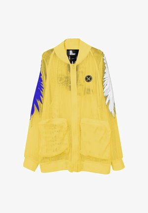 Chaqueta amarilla de malla con cremallera, grandes bolsillos delanteros, diseños de alas en azul y blanco en las mangas y un pequeño logo negro redondo en el pecho.