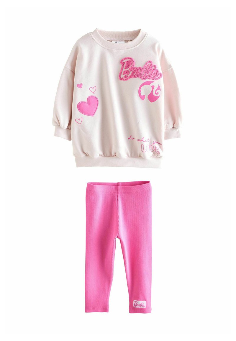 Lyserød langærmet sweatshirt med pink hjerter, Barbie-logo og lyserøde leggings med et lille Barbie-patch nær anklen.