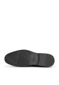 Suela de zapato negra con goma texturizada, que presenta ranuras horizontales y diagonales; logo de la marca embosado. Diseño liso y plano para mayor comodidad.