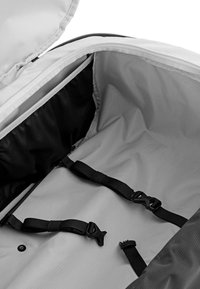 Grijze rugzakinterieur met een gladde textuur, voorzien van zwarte nylon banden, plastic onderdelen en een ritsvak voor organisatie.