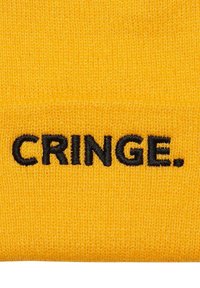 Kollane kudumine beanie pehme tekstuuriga, millel on musta tikandi tekst, mis ütleb ees "CRINGE."