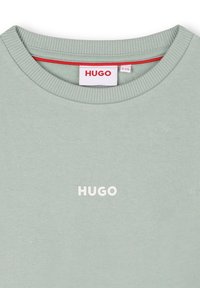 Light green sweatshirt featuring a crew neck, ribbed collar, and a white "HUGO" logo on the chest. Smooth texture with a relaxed fit.