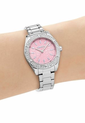 Orologio da polso in metallo argento con quadrante rosa, lunetta tempestata di cristalli e indici delle ore argentati indossato su un polso dalla pelle chiara che segna le 12:08.