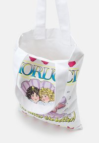 Biała torba płócienna z długimi uchwytami, z kolorowym ilustracyjnym wzorem przedstawiającym dwie dziewczyny, tekstem i grafiką muszli. Górne otwarcie bez zapięcia.