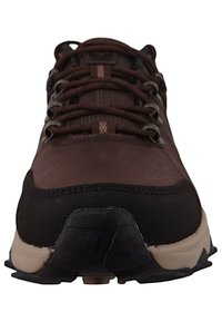 Brązowe buty sportowe z textured powierzchnią, wzmocnionym czubkiem i systemem sznurowania. Czarne akcenty i kontrastowa beżowa podeszwa.