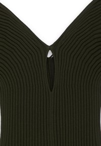 Dunkelgrünes, geripptes Oberteil mit V-Ausschnitt und einem Schlüsselaugen-Test an der Rückseite, das durchgehend über das Material mit strukturierten vertikalen Linien versehen ist.