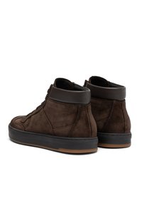 Une paire de baskets montantes en daim brun avec des cols rembourrés noirs, des semelles intermédiaires noires et des semelles extérieures en caoutchouc gomme, présentée sous un angle arrière.