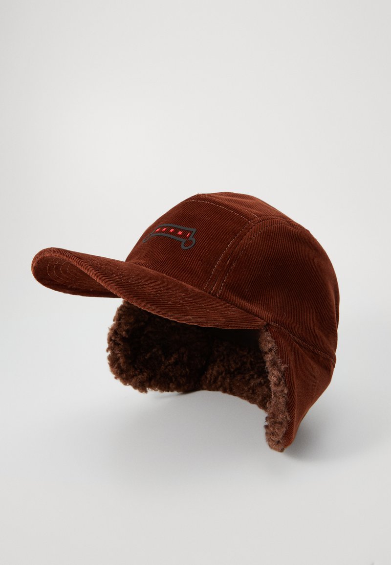 Brown corduroy cap with a soft fur lining underneath the brim and embroidered logo in red and black. Features a curved visor and ear flaps.