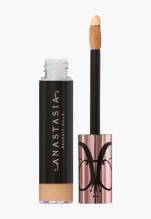 Vloeibare concealer in een doorzichtige fles met een zwarte dop. De applicator heeft een pluizige spons. De merknaam staat in elegante letters.