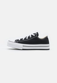 Schwarze Leinensneaker mit weißer Gummisohle, schwarz-weißen Schnürsenkeln und einem schmalen Profil. Verfügt über gestickte Akzente und minimalistisches Branding.
