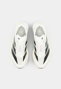 White athletic shoes with black and green accents, mesh upper, and textured detailing. Features a rounded toe and lightweight sole.