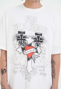 T-shirt bianco con una grande croce, cuore rosso etichettato "Los Angeles", due croci nere e teschi punk sbiaditi con il testo "Punk Non È Morto".
